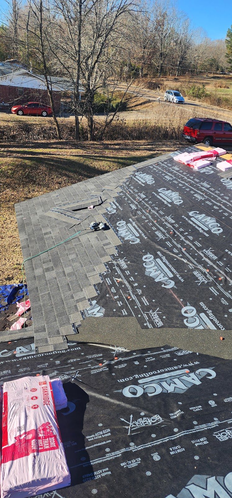 Synthetic underlayment being installed over a roof deck before the shingles go on